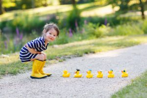 toddler playing with rubber ducks outside